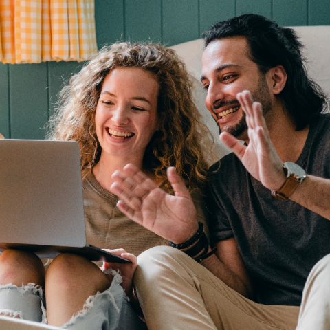 Man en vrouw met laptop zitten op de grond in een woonkamer